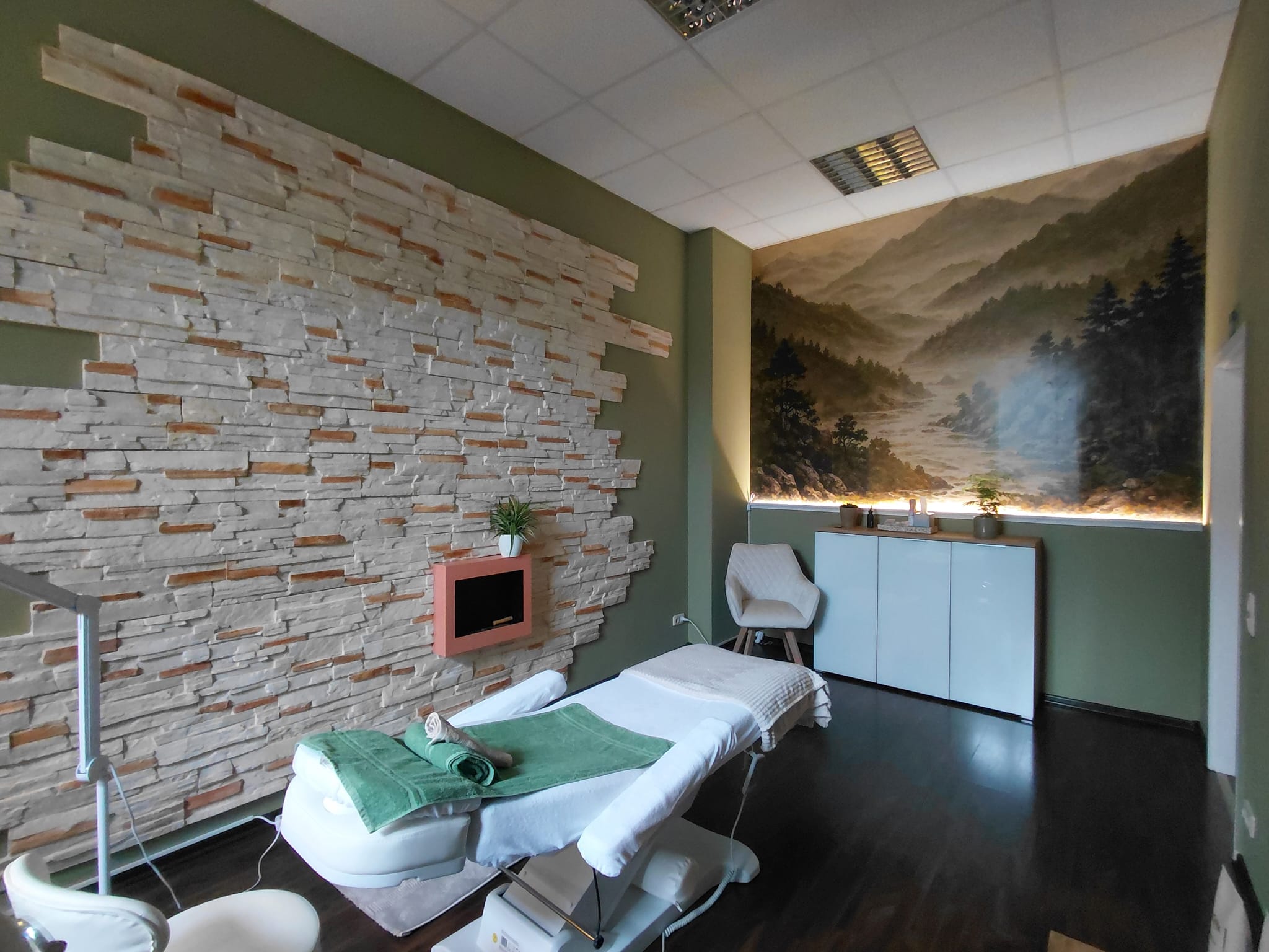 Wellnessraum mit Massageliege und Naturwandbild